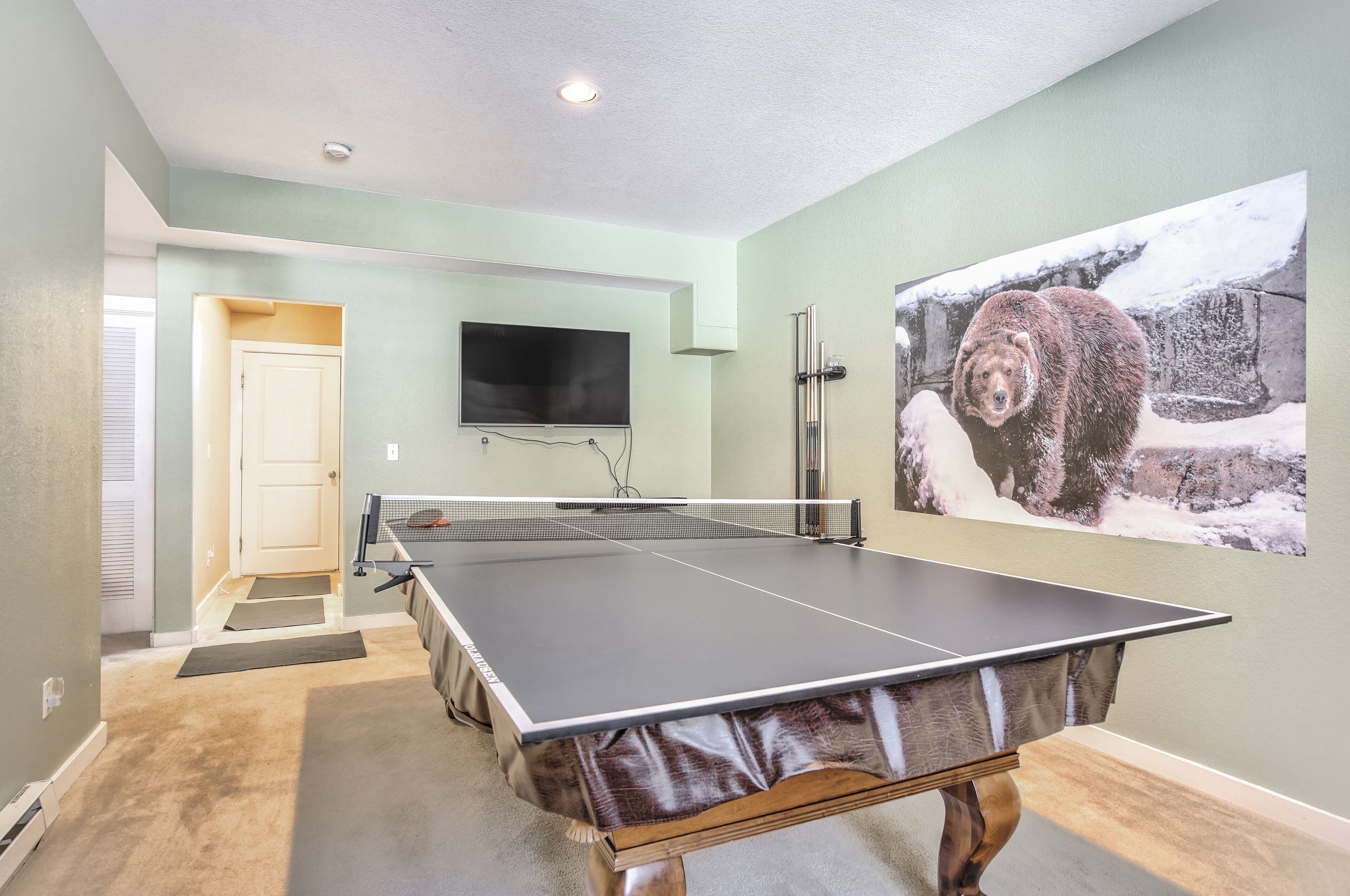 Une table de ping-pong dans une pièce où est accroché un tableau représentant un ours.