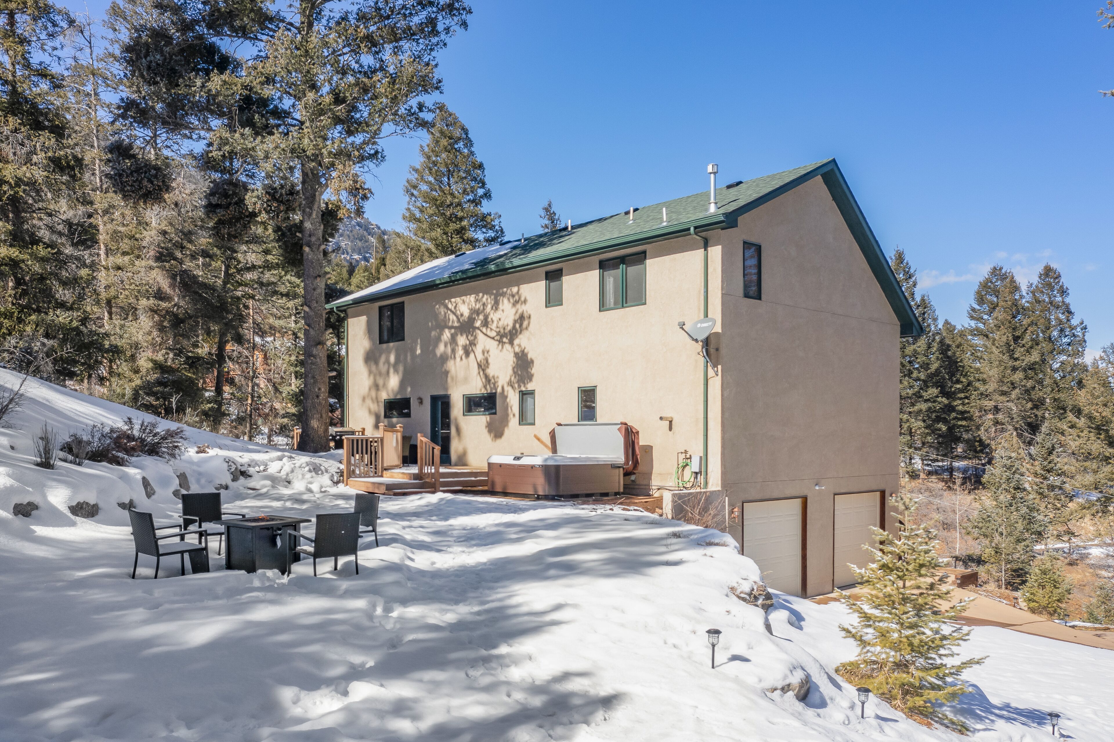A two-story building with a sloped roof, a patio with outdoor furniture, and a snow-covered ground.