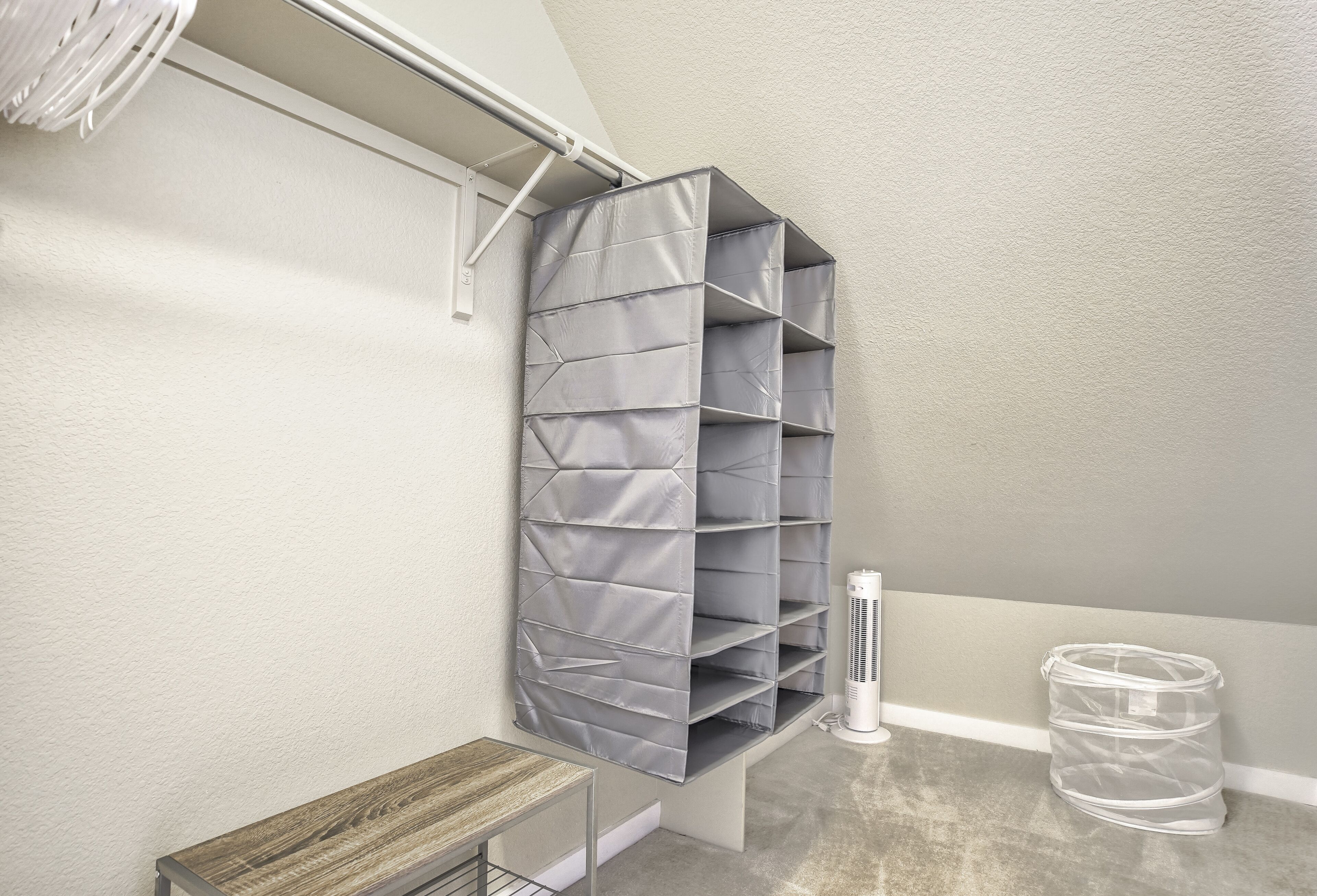 Um módulo de canto com várias prateleiras, uma pequena mesa e um cesto de plástico transparente.
