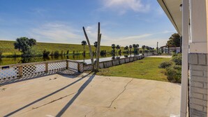 A concrete deck with a view of a lake, a fence, and a grassy area. - Sun-Soaked Okeechobee Retreat w/ Canal Views! (Okeechobee)