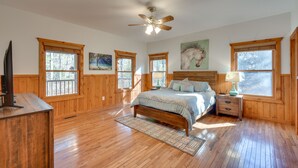 A bedroom with wooden floors, a bed, a nightstand, a desk, and a ceiling fan. - Hiawassee Vacation Rental w/ Grill ~ 9 Mi to Lake! (Hiawassee)