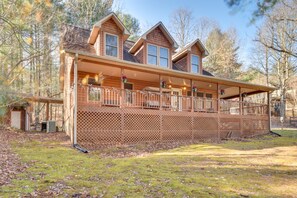 A two-story log cabin with a covered porch and a fenced deck. - Hiawassee Vacation Rental w/ Grill ~ 9 Mi to Lake! (Hiawassee)