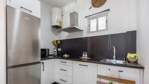 Eine moderne Küche mit einem Edelstahl-Kühlschrank, einem Einbauofen, einer Mikrowelle, einem Spülbecken und einer Bank mit einer Pflanze.