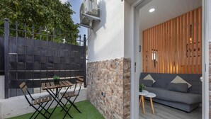 Eine Terrasse mit Tisch und Stühlen, eine Steinmauer, ein graues Sofa und ein Holzzaun.