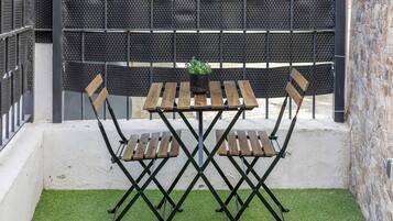 Une terrasse avec une table et des chaises, une plante en pot et un mur à motifs en arrière-plan.