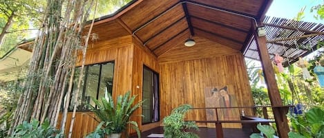 Un bâtiment en bois doté d’un toit en pente, entouré de bambous et de diverses plantes.