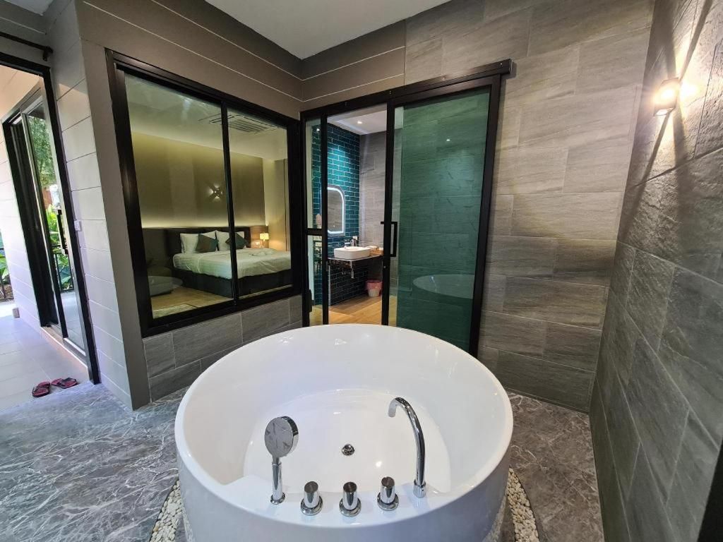 Un baño moderno con una bañera grande, zona de ducha con mampara de vidrio y lavamanos a la vista.