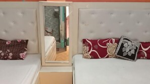A bedroom with two beds, a mirror, and a wardrobe. - MAA VAISHNO GUEST HOUSE (Varanasi)