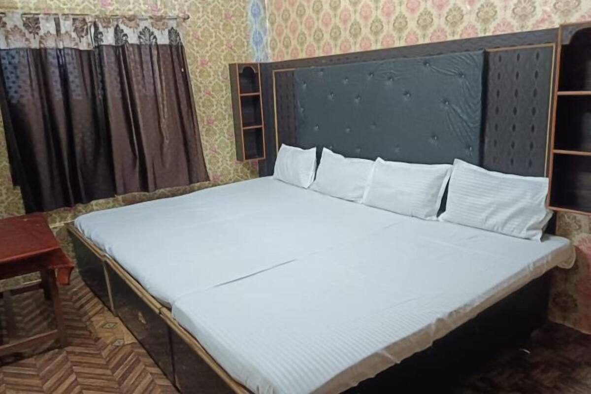 A bedroom with a large bed, a wooden nightstand, and a patterned wall.