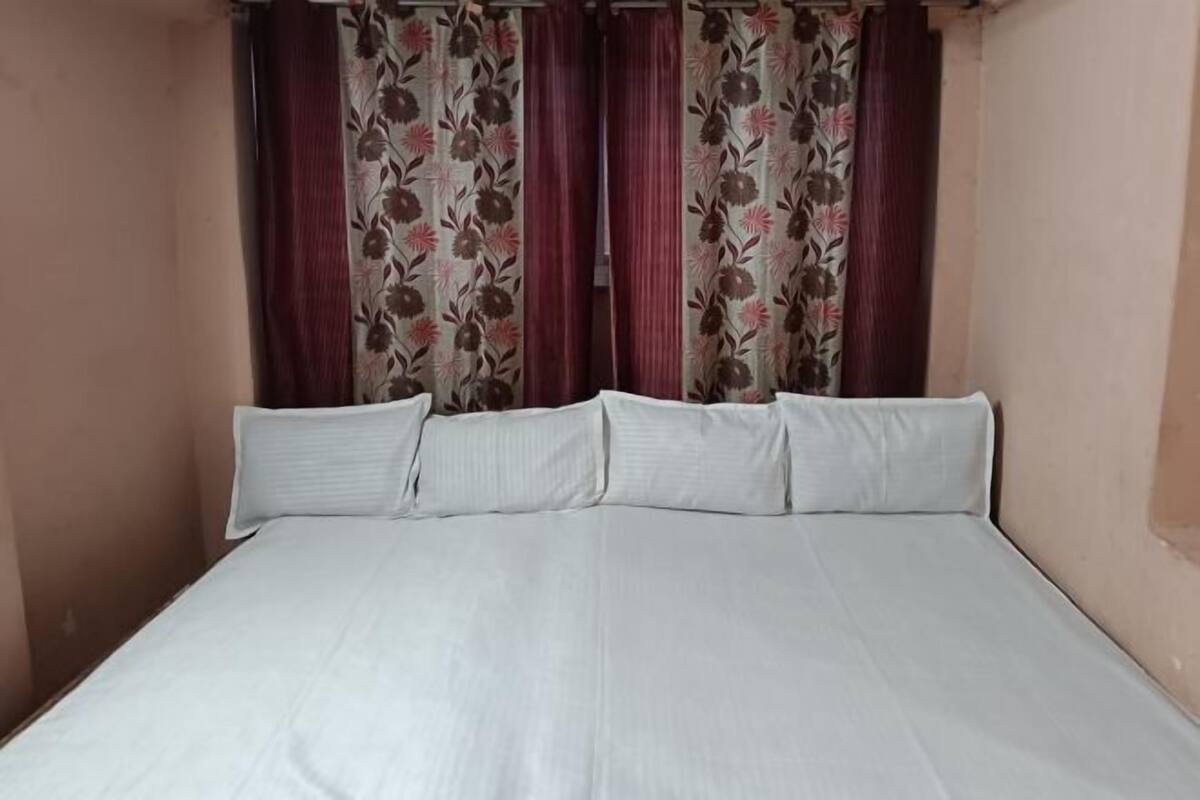 A single bed with white bedding and floral curtains.