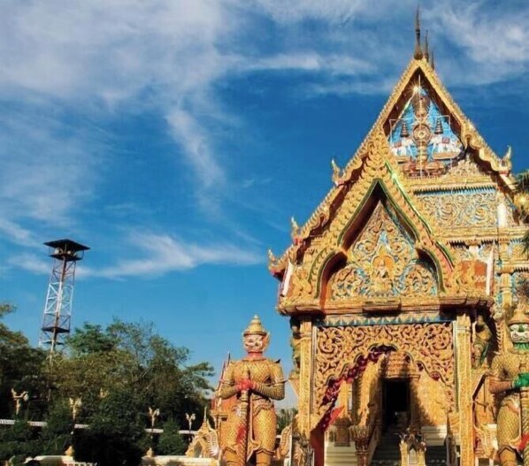 A temple with intricate architecture and a tall structure in the background. - My Room Nakhonpathom (Nakhon Pathom)