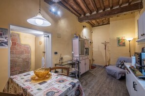 Uma cozinha acolhedora com uma mesa de jantar, uma geladeira e um pequeno espaço para sentar.