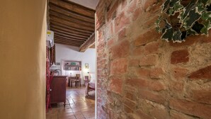 A narrow hallway with a brick wall and wooden beams, leading to a room with a bed and a desk. - Holiday Home 'La Casa Gialla Di Buonconvento' with Wi-Fi and Air Conditioning (Buonconvento)