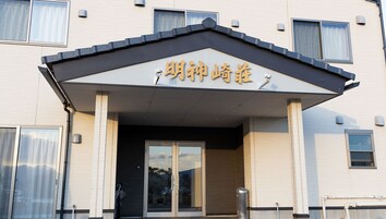 Un edificio con un letrero que dice '明神山荘' y un acceso cubierto con puertas de vidrio.