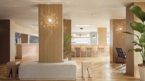 A modern interior with wooden floors, a central seating area, and a kitchen in the background. - Nest Hotel Ishigaki Maesato Beach (Ishigaki)
