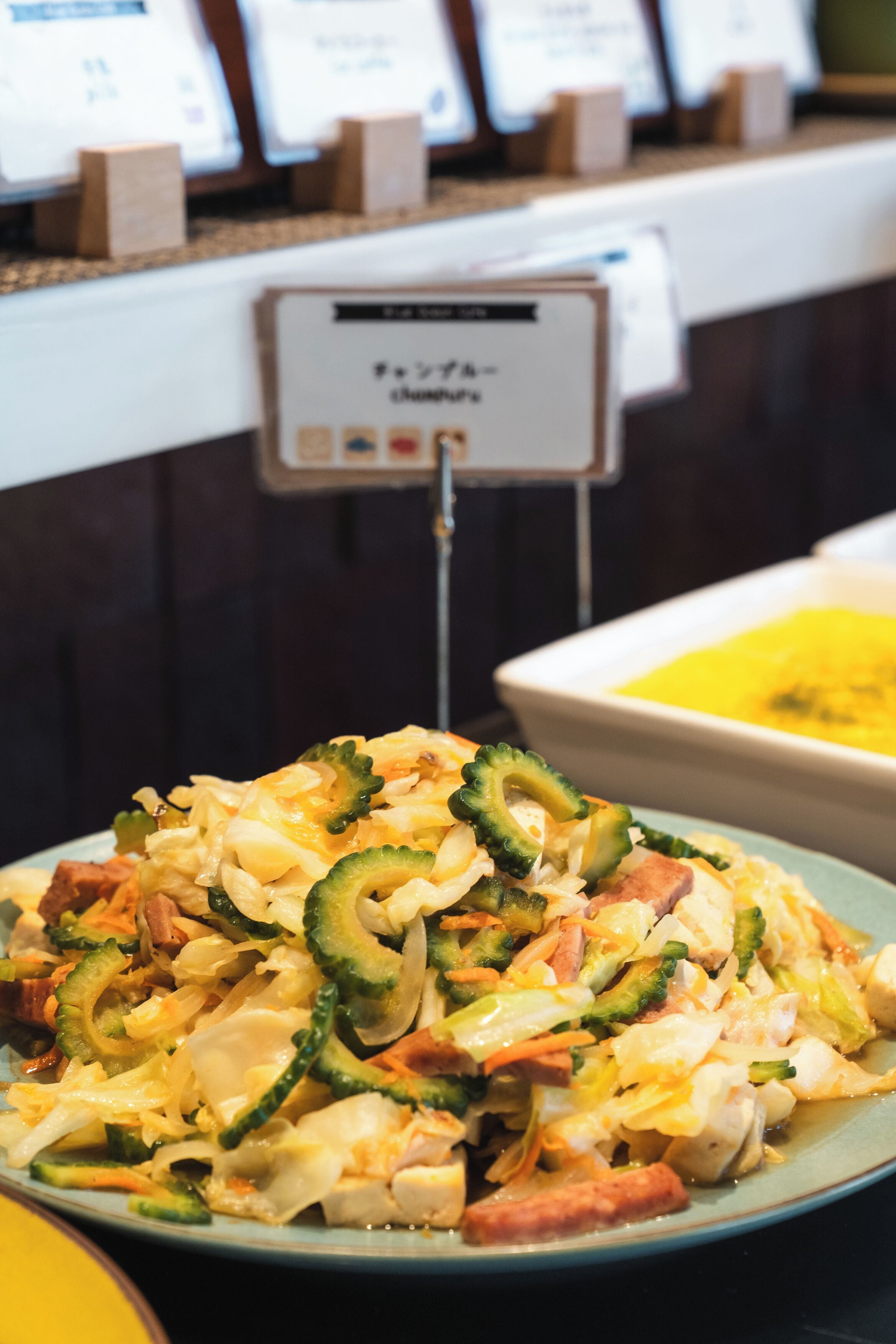 Ein Buffet mit verschiedenen Speisen, darunter ein Teller mit Gemüse und ein Schild, das den Buffetbereich kennzeichnet.