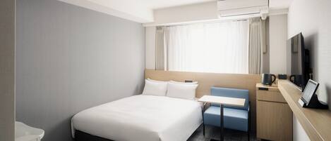 A hotel room with a bed, a desk, a chair, a TV, and a window with curtains.