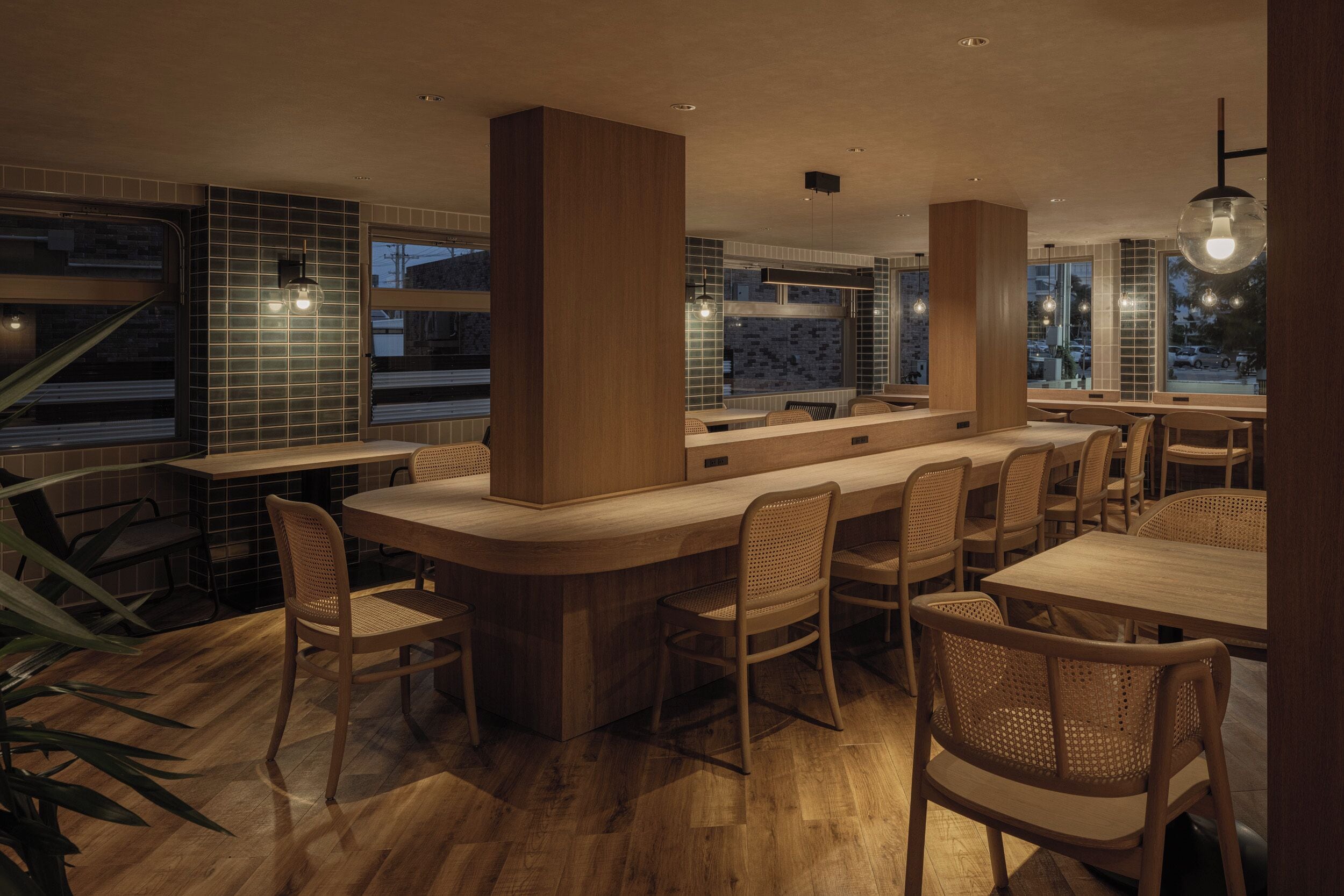 Un restaurant moderne avec un long comptoir, des chaises en bois et de grandes fenêtres.