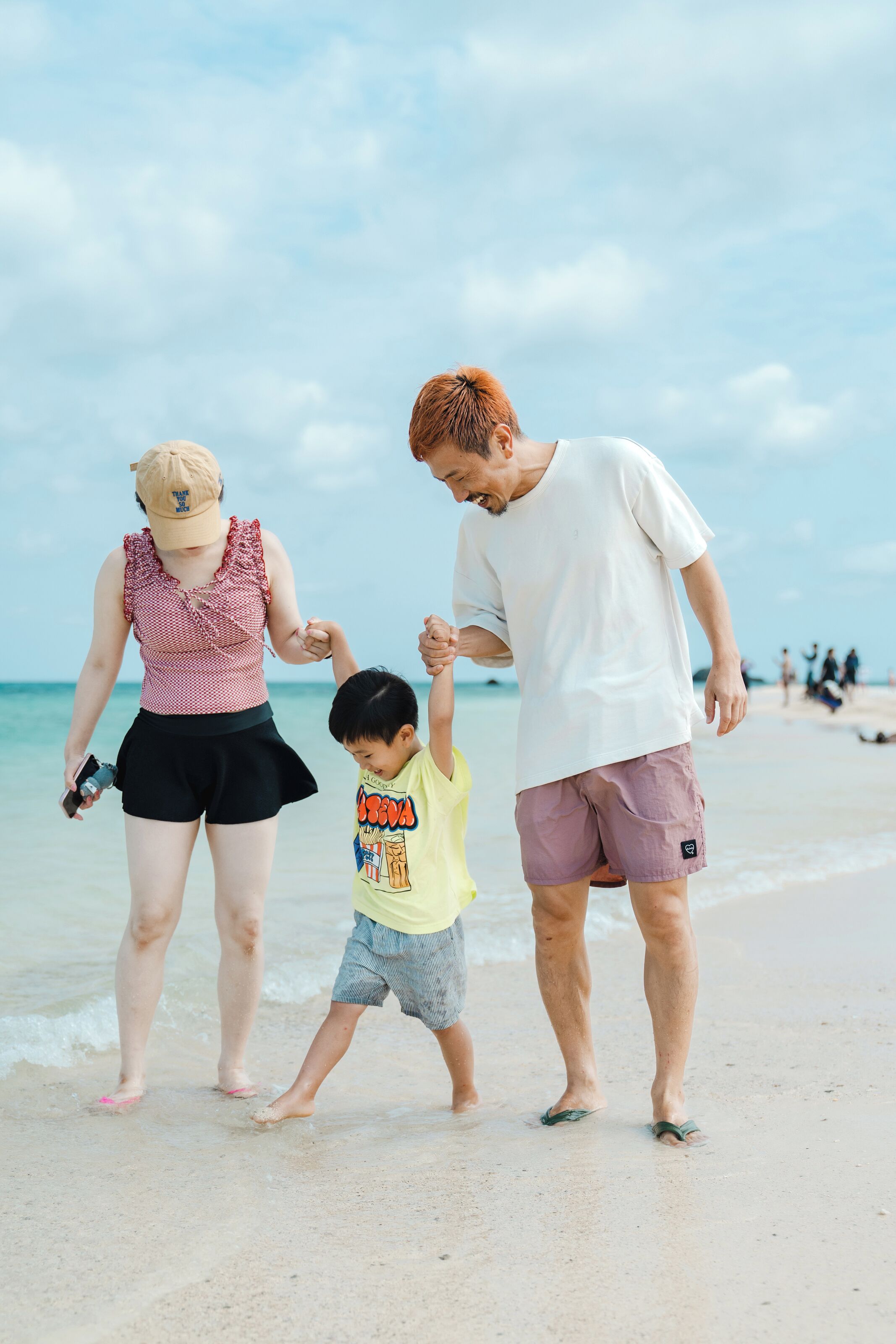 Una famiglia che cammina su una spiaggia sotto cieli sereni.