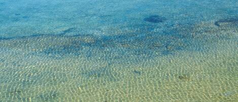 Vista despejada de una playa con aguas poco profundas y dibujos de arena visibles.