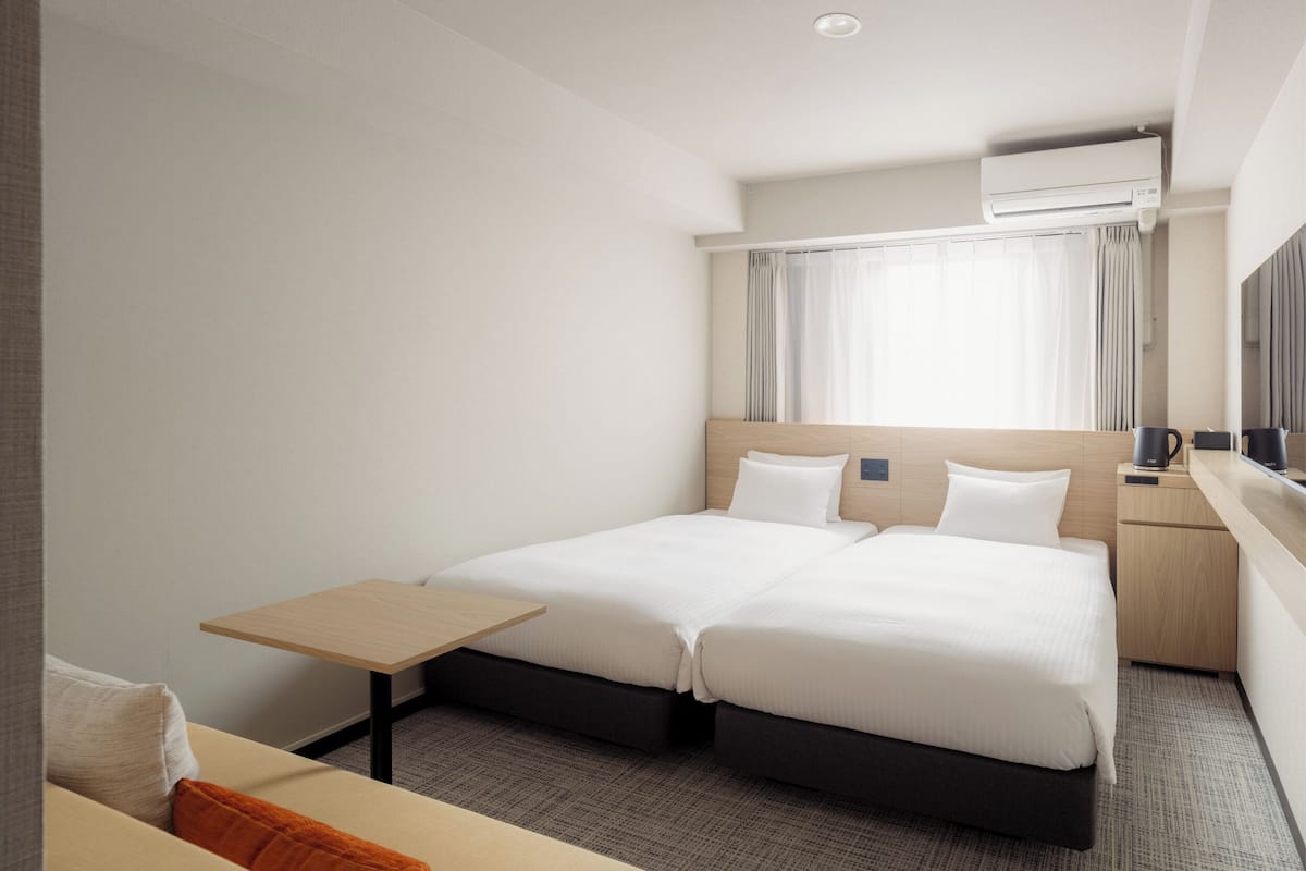 Ein Hotelzimmer mit Doppelbett, einem kleinen Tisch, einer Couch und einem Fernseher.