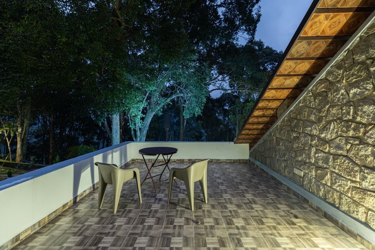 An outdoor patio with a stone wall, a wooden sloped roof, and a herringbone-patterned floor.