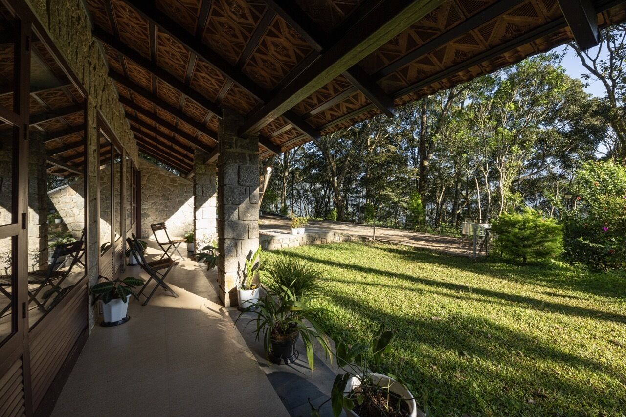 A covered outdoor area with stone pillars, wooden benches, and potted plants.