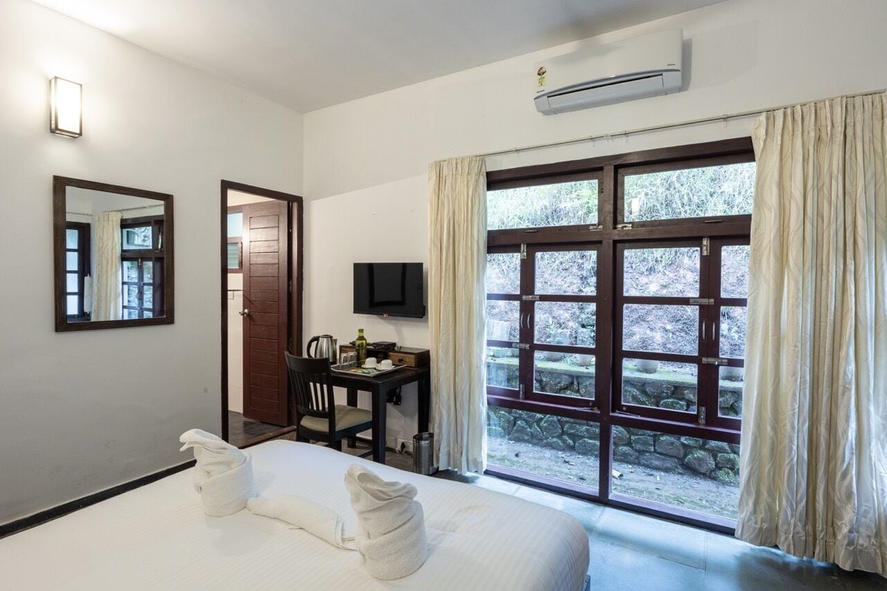 A hotel room with a bed, a desk, a chair, a television, and a window with curtains.