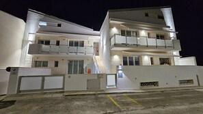 Ein mehrstöckiges Gebäude mit Balkonen, einer Treppe und einem Parkplatz.
