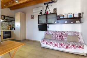 A kitchen with a wooden table, a sofa with a patterned cover, and a mounted telescope.