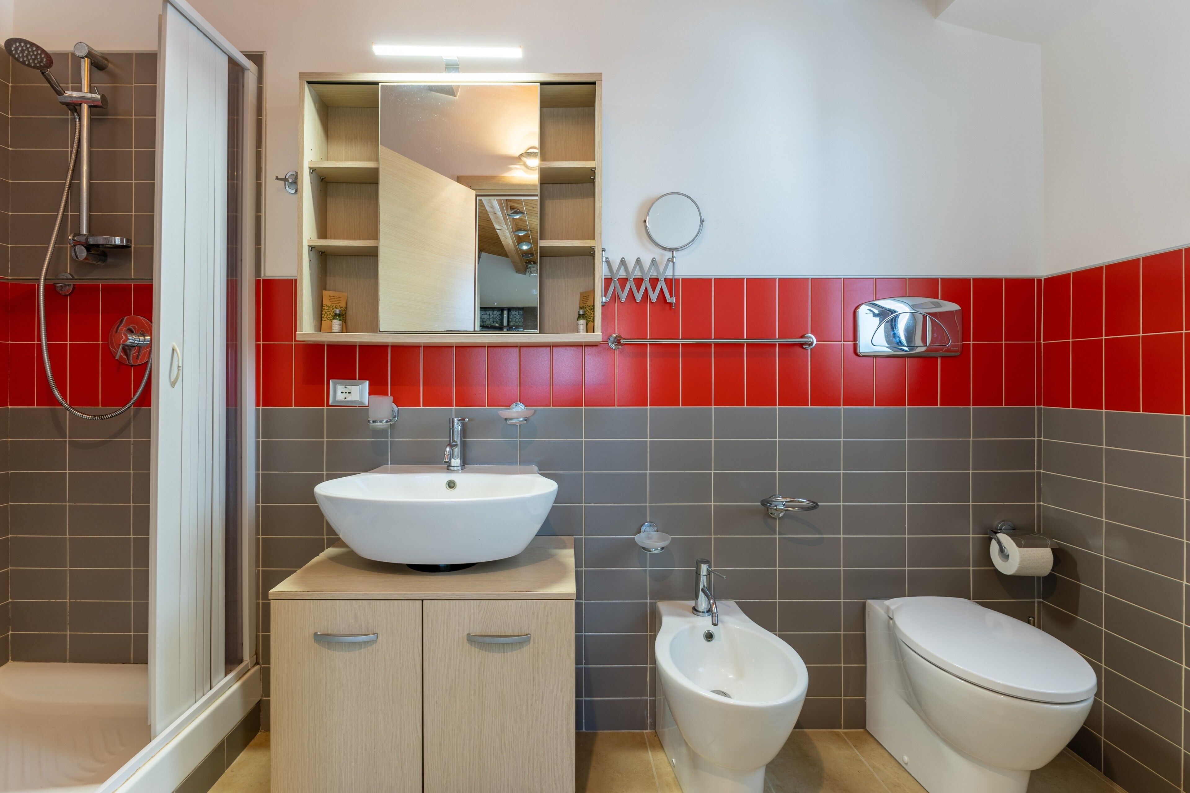 Ein modernes Badezimmer mit Dusche, Waschbecken, Bidet, Toilette und Spiegel.