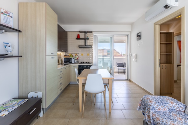 Une cuisine compacte comprenant une table et des chaises, un petit réfrigérateur et un four à micro-ondes.