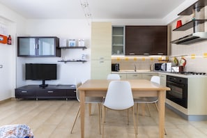 Une cuisine moderne équipée d’une table à manger, de chaises, d’un téléviseur et d’appareils électroménagers intégrés.