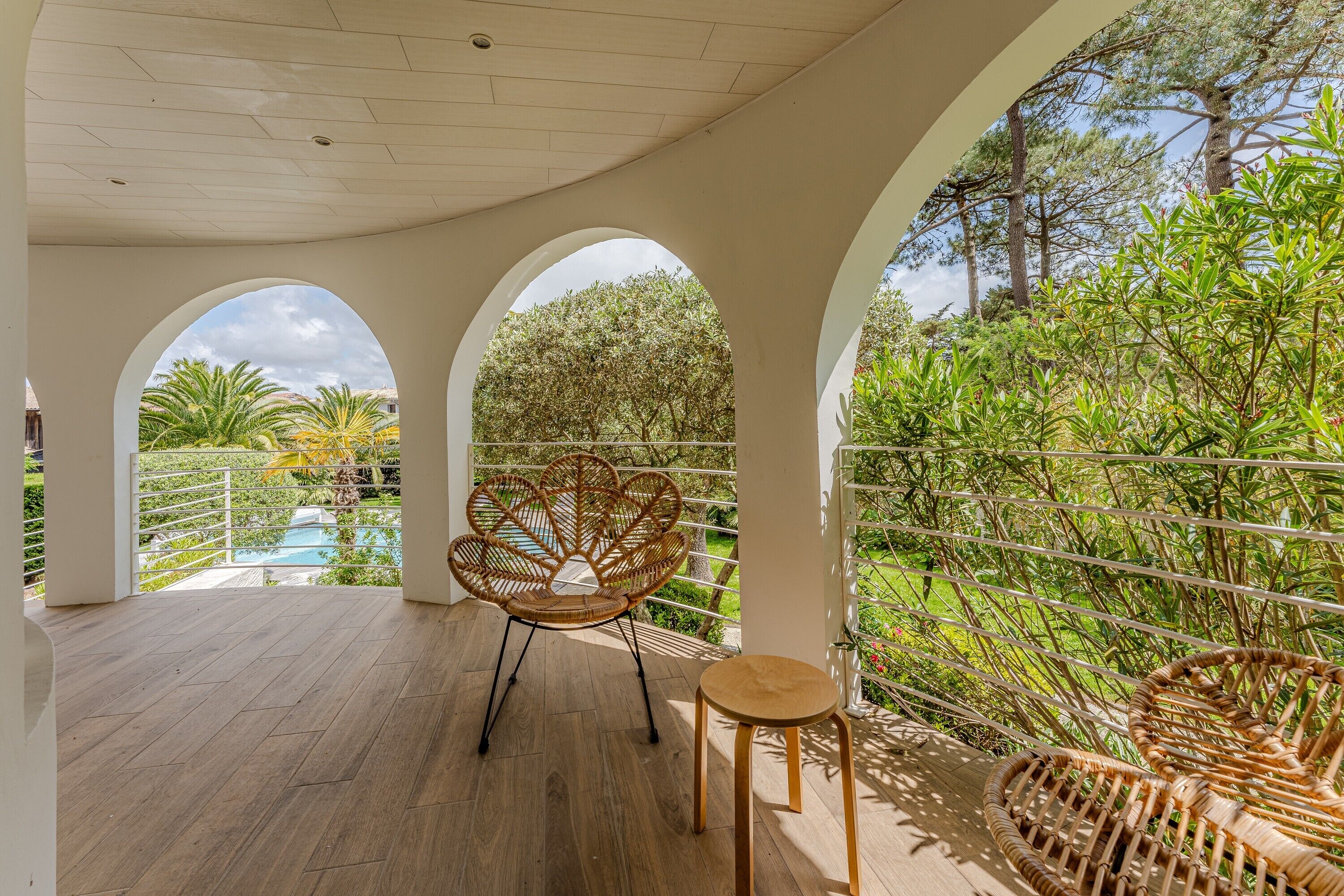 A covered outdoor area with a wooden floor, a wicker chair, and a small table.