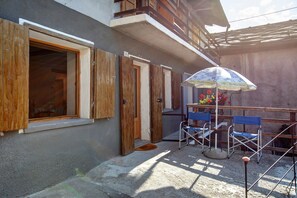 Un bâtiment avec des volets en bois, un balcon et une table avec des chaises à l’extérieur.