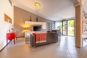 A modern living room with a sofa, TV, and a red chair.