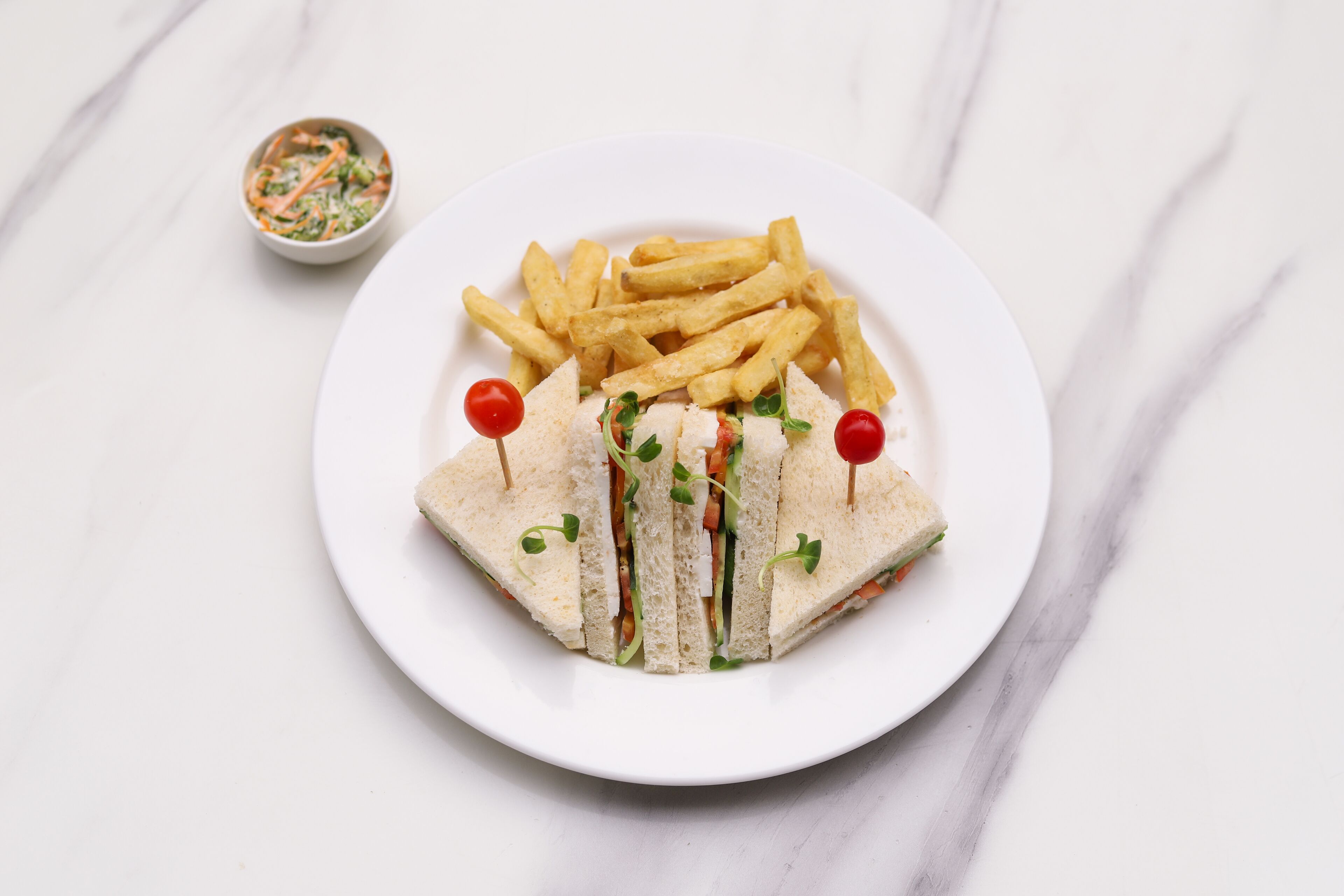 A plate of sandwiches with cherry tomatoes and a side of French fries.