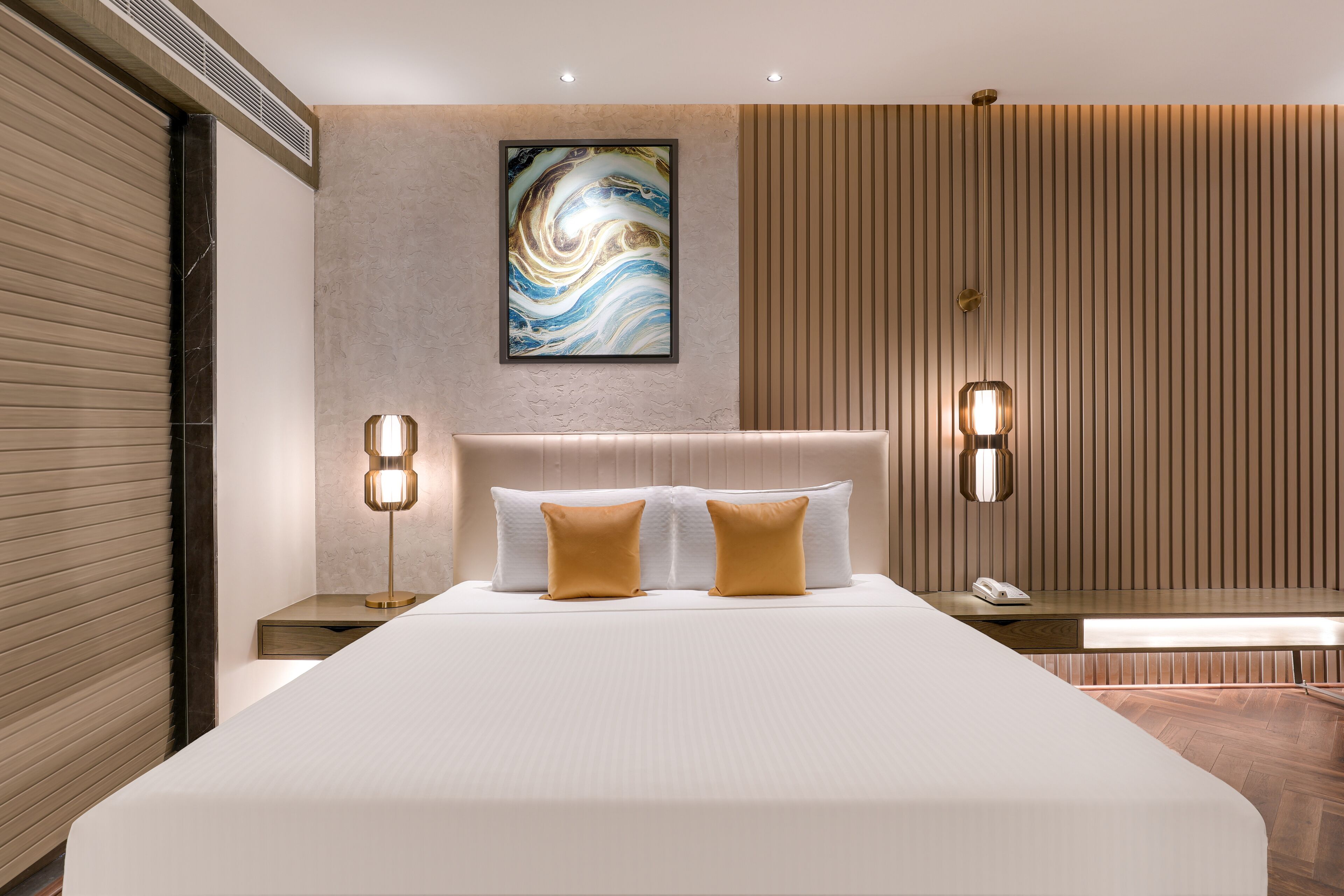 Una habitación de hotel moderna con una cama grande, dos mesitas de noche, una obra de arte colgada en la pared y un revestimiento de pared de madera.