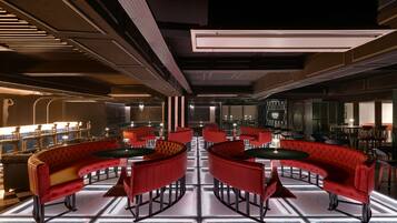 A modern interior with red upholstered seating, a checkered floor, and a central table.