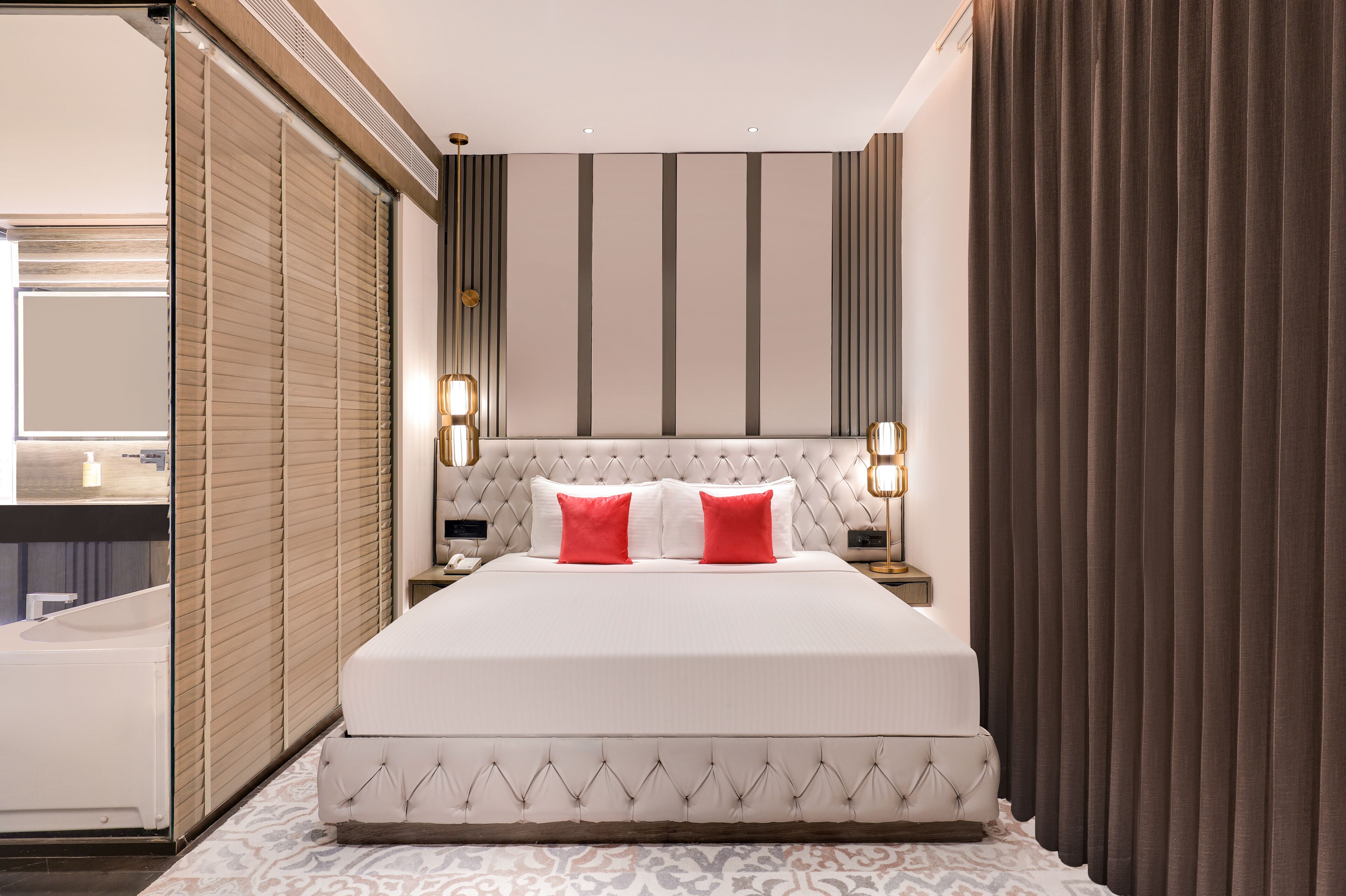 A modern hotel room with a large bed, a bedside table, a nightstand, and a bathroom visible through a sliding door.