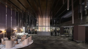Eine großzügige Lobby mit modernem Design, ausgestattet mit einer zentralen Sitzecke mit Sofas und einem Couchtisch, einem Empfangsbereich und einem großen Fenster mit Blick ins Innere.