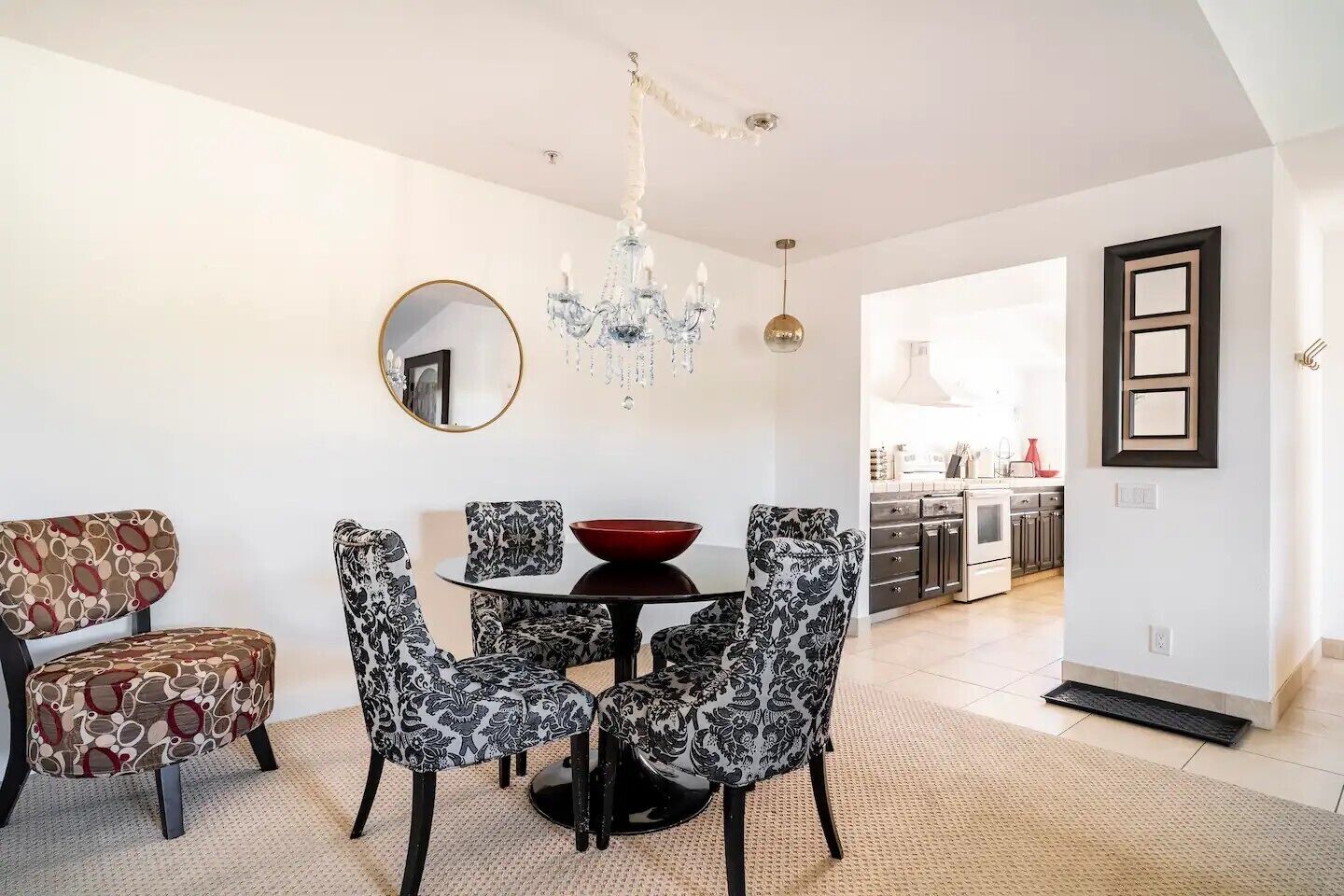 Un coin repas avec des chaises à motifs, une table ronde et un lustre.