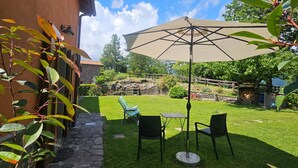 A patio with a table and chairs, an umbrella, and a stone wall. - Holiday Home 'La Casina Rossa Della Fornace' with Mountain View, Private Garden & Wi-Fi (Cutigliano)