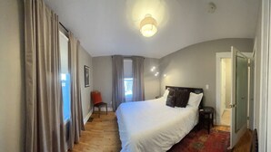 Una camera da letto con un letto grande, un tavolino, una sedia e una finestra con tende.