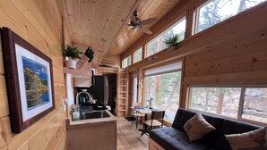 A cabin interior with a kitchen, dining area, and a sofa. - Ptarmigan Tiny Home (#10) at The Woolly Bugger Inn (Estes Park)