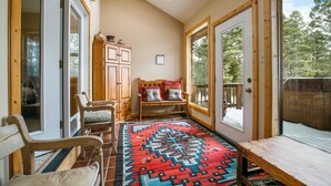 A cozy room with a large window, a wooden bench, a rug, and a cabinet. - Cimmaron Sky by Velo (Angel Fire)