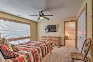 A bedroom with a bed, a dresser, a chair, a ceiling fan, and a TV.
