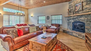 A cozy living room with leather sofas, a stone fireplace, and wooden flooring. - Cimmaron Sky by Velo (Angel Fire)