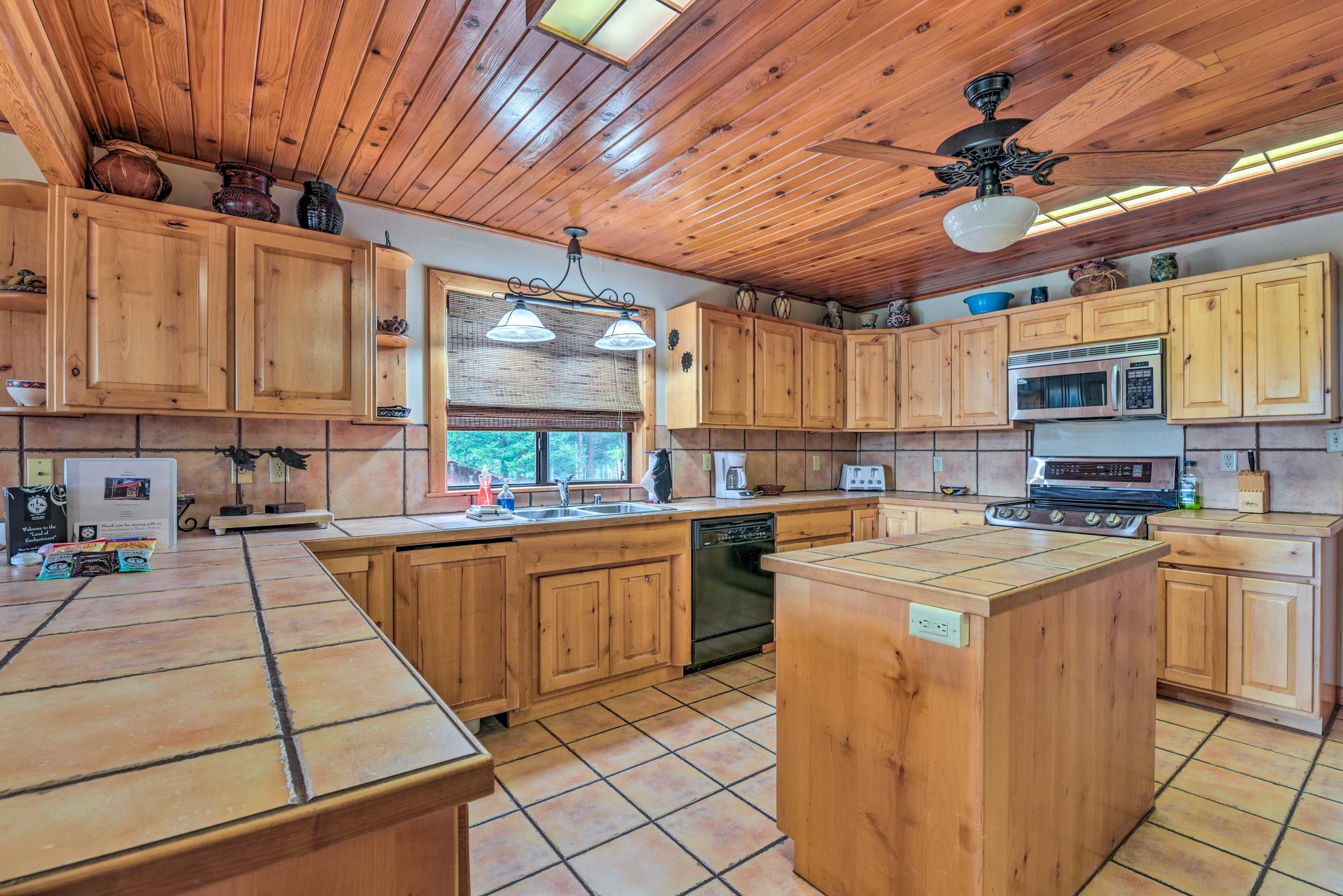 A kitchen with wooden cabinets, a central island, a ceiling fan, and a window providing natural light.