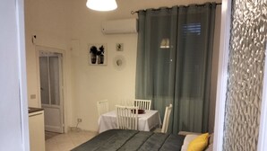 Une chambre à coucher comprenant un lit, une table de chevet, une chaise, une petite table et une fenêtre avec des rideaux.